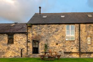 a stone house with a picnic table in front of it at Bryn Lon Bach in Caeʼr-geiliog
