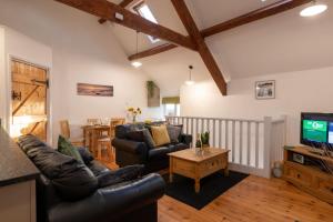 a living room with leather furniture and a tv at Bryn Lon Bach in Caeʼr-geiliog