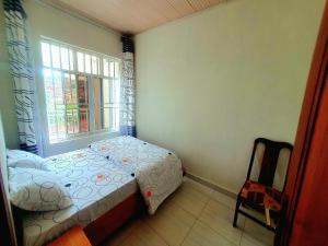 a bedroom with a bed and a window and a chair at Park View Perch Guest house with Balcony near Downtown in Kigali