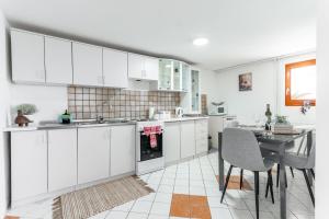 a kitchen with white cabinets and a dining table at Apartman Suman in Vukovar