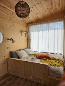 a bed in a wooden room with a window at Retezat83 Sunshine tiny home , adults only in Râu de Mori