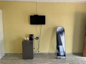 a room with a mirror and a tv on a wall at The Arrose Guest House in Kwamhlanga