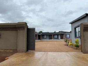 a house with a gate in front of a driveway at The Arrose Guest House in Kwamhlanga