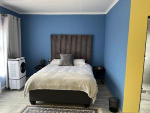 a blue bedroom with a bed with a wooden headboard at The Arrose Guest House in Kwamhlanga