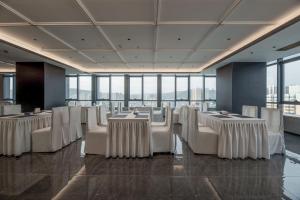 a banquet hall with white tables and chairs and windows at Maihao Hotel in Rujiazhuang
