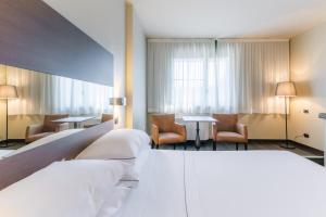 a hotel room with two beds and tables and chairs at Smart Hotel King, by R Collection Hotels in Varedo