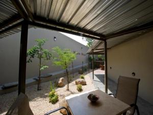 a patio with a table and chairs under a wooden ceiling at Monte Bello Guesthouse in Windhoek
