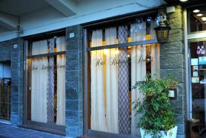 a store window with curtains and a plant in front at Hotel Domus in Maranello