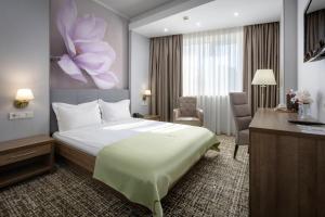 a hotel room with a large bed and a desk at Renion Hills Hotel in Almaty