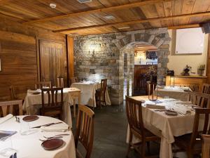 a restaurant with tables and chairs and a stone wall at Hotel Maison Saint Jean in Courmayeur