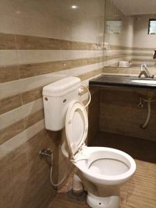 a bathroom with a white toilet and a sink at Hotel HV Palace in Bhuj