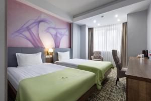 a hotel room with two beds and a desk at Renion Hills Hotel in Almaty