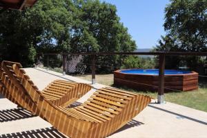 a group of wooden benches on a patio with a pool at La Petite Grande in Lurs