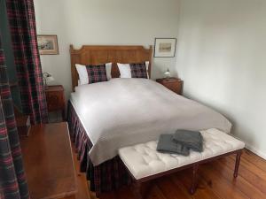 a bedroom with a bed with white sheets and a bench at B&B Fiddler's Inn in Neuruppin