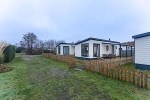 a house with a fence next to a yard at Duinhoeve chalet Schelp in Burgh Haamstede