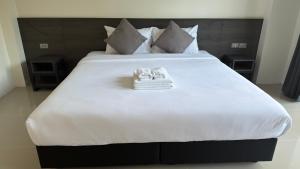 a large white bed with two towels on it at A House Thalang เอ เฮ้าส์ ถลาง in Thalang