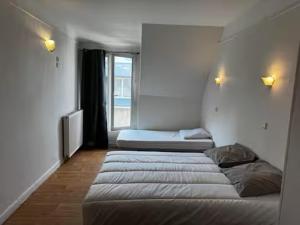 a room with two beds and a window at Welcome in Issy-les-Moulineaux