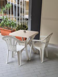a white table and two chairs in a room with plants at Monti Guest House Alghero in Alghero