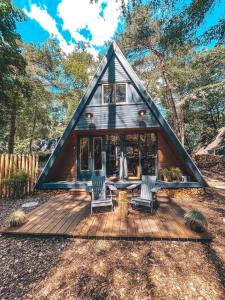 a tiny house in the woods with a wooden deck at Het Punthuisje in Lanaken