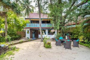 a house with a hammock and chairs in front of it at Kai's Beachfront Villa in Gili Islands