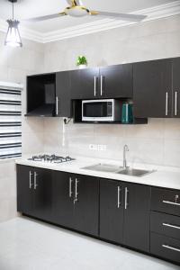 a kitchen with black cabinets and a sink and a microwave at Nii Amar Residences in Ofako +5 photos
