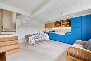 a kitchen with blue cabinets and a table with chairs at Les Volets Bleus de Trouville - Centre - Plage in Trouville-sur-Mer