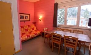 a dining room with a table and a couch at Résidence Vacancéole Les Monts Jura in Lélex