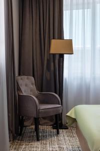 a chair sitting next to a lamp in a bedroom at Renion Hills Hotel in Almaty +37 photos