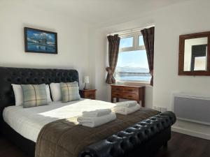 a bedroom with a bed with a leather couch and a window at Argyll Hotel in Ullapool
