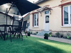 a pair of chairs and an umbrella in front of a house at La bulle des Viennes MAISON CLIMATISEE - CHAMPAGNE in Sainte-Savine