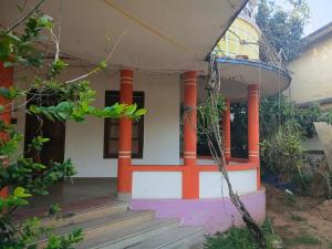 a house with orange columns and a porch at First Alleppey homestay in Alleppey