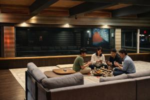 a group of people sitting around a table in a room at Moonbay Beach Villa in Lake Toya
