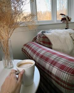 a person holding a cup of coffee on a table at La Villa Rustique-2 in Notre-Dame-du-Lac