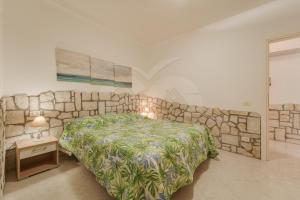 a bedroom with a bed and a stone wall at Azzurro Mare a Seccheto - Goelba in Seccheto