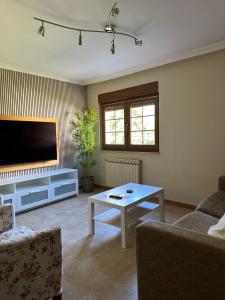 a living room with a flat screen tv and a table at Casa Las Coberazas in Arenas de Cabrales