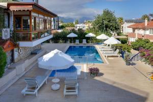 a pool with chairs and umbrellas next to a building at NATURELLA APART HOTEL in Kemer