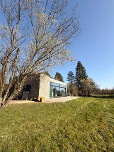 a building with glass windows on a grass field at Moulin de Baillonville in Baillonville