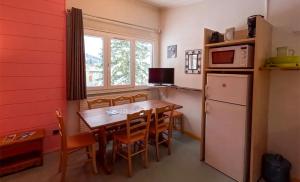 a kitchen with a dining room table and a refrigerator at Résidence Vacancéole Les Monts Jura in Lélex +17 photos