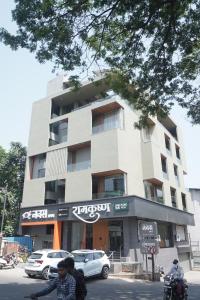 a building with cars parked in front of it at Hotel Navas Inn- Pure Veg, Kolhapur in Kolhapur