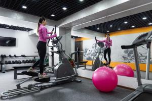 two women exercising on exercise bikes in a gym at Renion Hills Hotel in Almaty