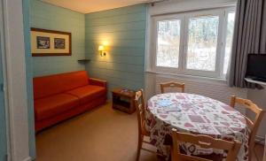 a living room with a table and a couch at Résidence Vacancéole Les Monts Jura in Lélex