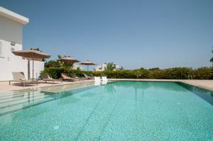 a swimming pool with chairs and umbrellas at J&K Villa in Kalithies
