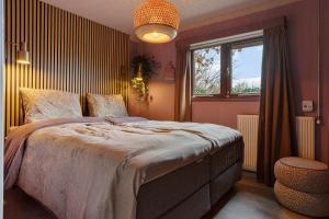 a bedroom with a large bed and a window at Boshuisje met privétuin bij Kruisbergse bossen Achterhoek in Hummelo