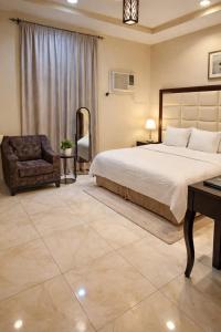 a bedroom with a large bed and a chair at Roaa Apartments شقق مخدومة in Al Qunfudhah +11 photos