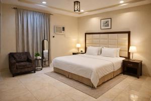 a bedroom with a large bed and a chair at Roaa Apartments شقق مخدومة in Al Qunfudhah