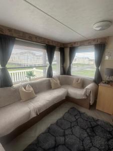 a living room with a couch and a large window at Sandylands caravan park in Stevenston