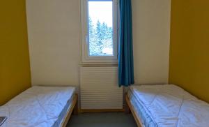 two beds in a room with a window at Résidence Vacancéole Les Monts Jura in Lélex
