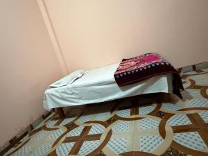 a small bed in a corner of a room at New Giri Homestay in Nichlaul