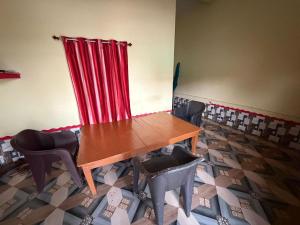 a table and chairs in a room with a red curtain at New Giri Homestay in Nichlaul