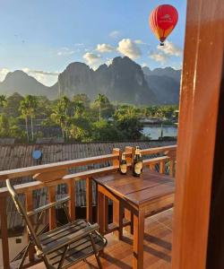 a table and a chair on a balcony with a hot air balloon at city mountain hotle in Vang Vieng